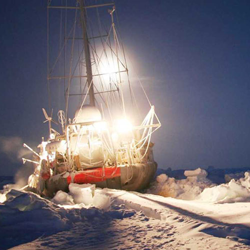 Segelbåt fast i isen i Arktis. Utrustad med en vindgenerator från tyska kvalitetstillverkaren Superwind.