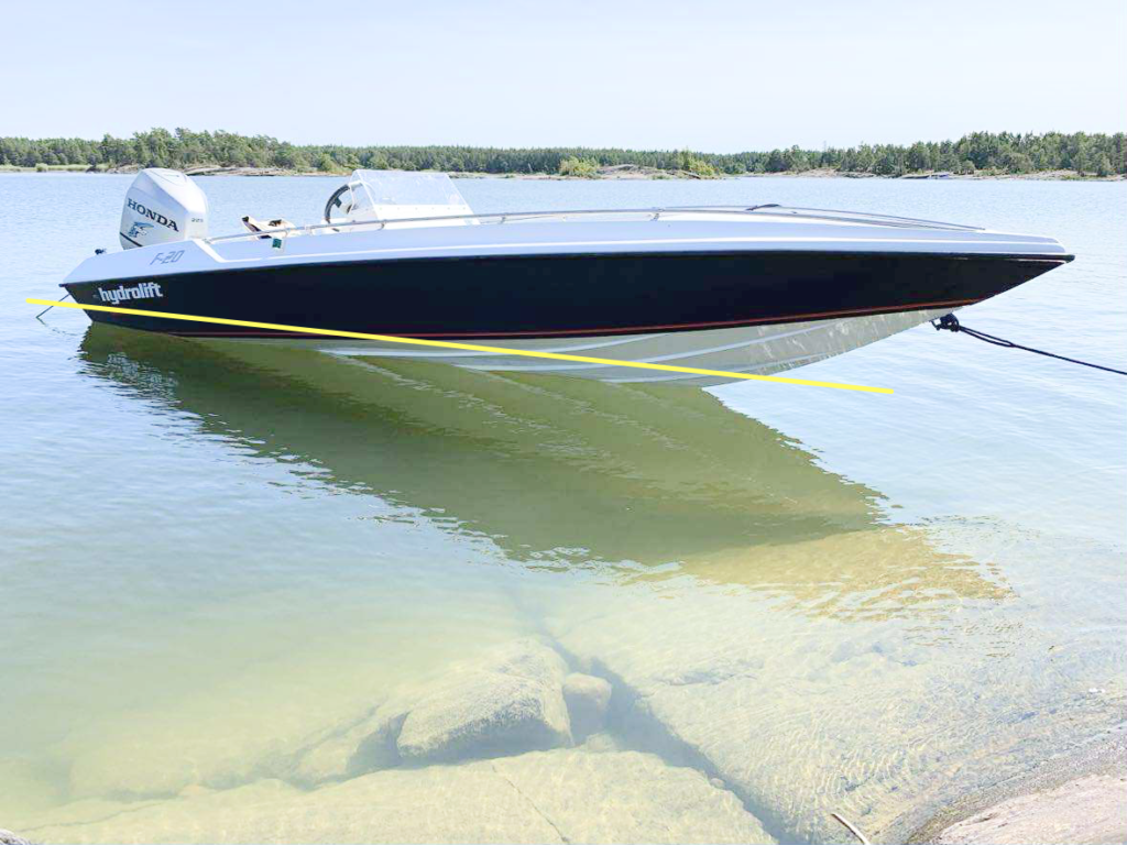 Hydrolift F20 på bilden är målad efter skrovform i stället för en riktig vattenlinje. Den ljusgula linjen visar hur vattenlinjen ska ligga: parallellt med vattenytan och minst ca 5 cm ovanför (gärna 7–10 cm). Under vattenlinjen används epoxifärg som tätskikt, och ovanför målas 2K polyuretan som Double Coat.