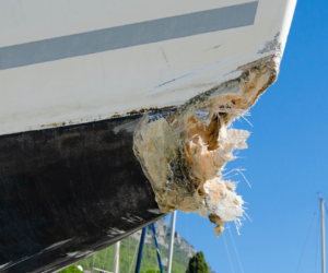 Skadad stäv på glasfiberbåt före reparation med epoxispackel